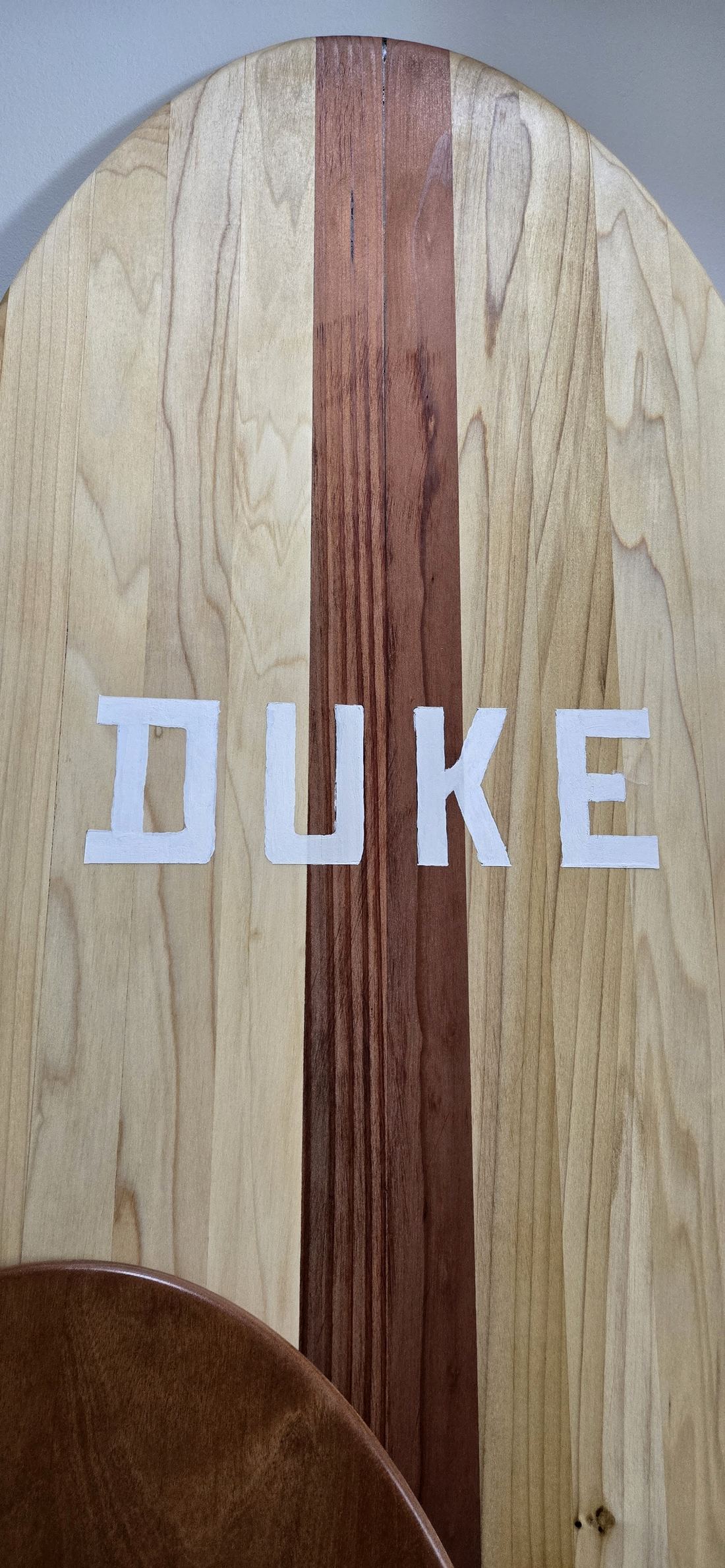 Close on a striped wooden board, DUKE inlaid in white.
